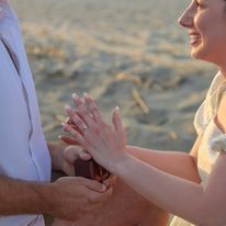 A bride and groom are holding hands on the beach.