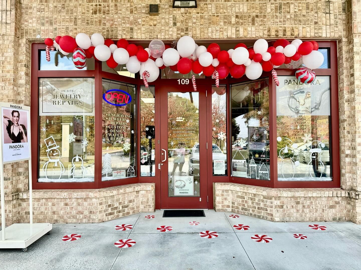 A store front with red and white balloons hanging from the ceiling.