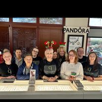 A group of people are posing for a picture in a pandora store.