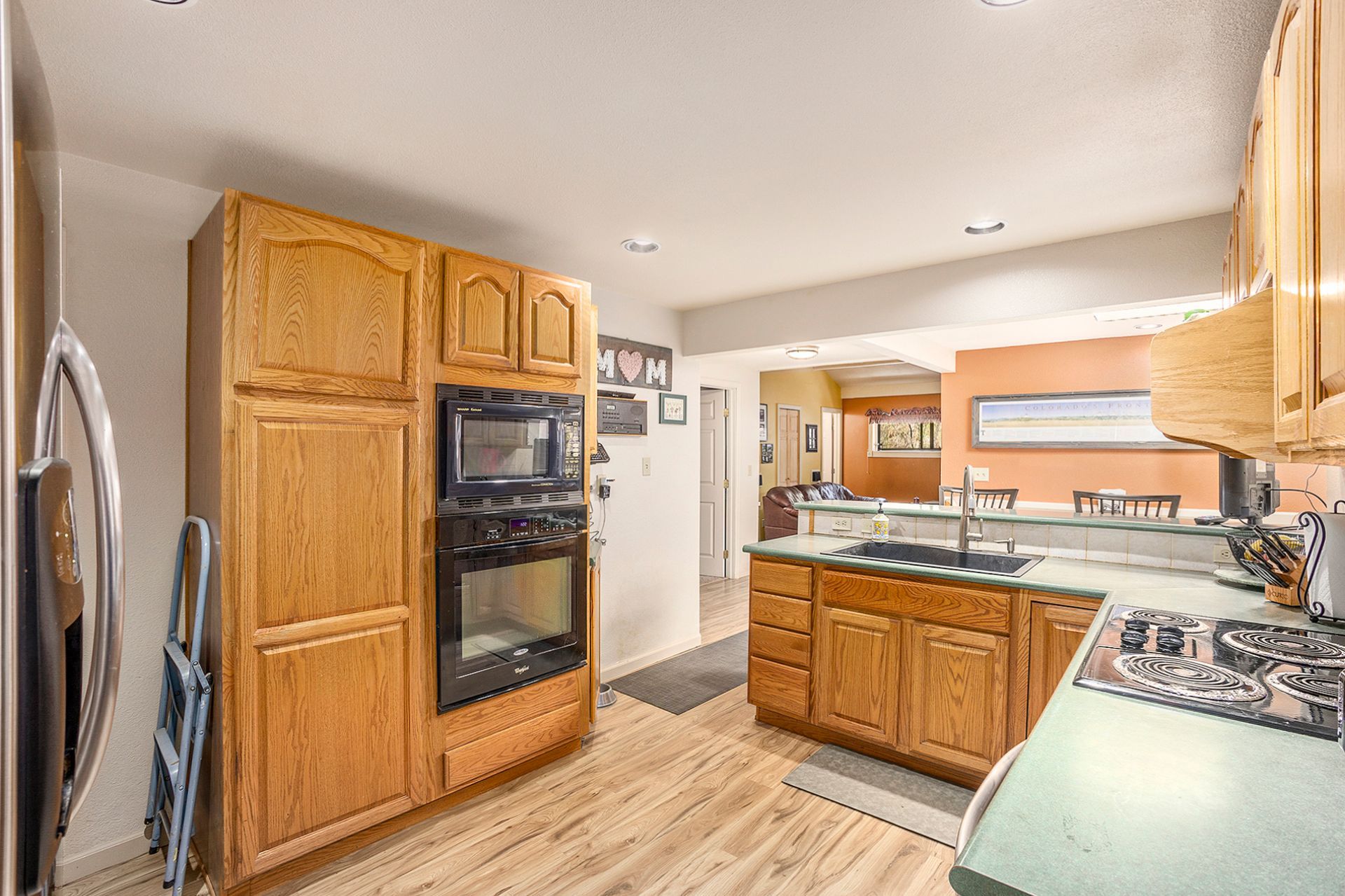 A kitchen with wooden cabinets , a stove , a refrigerator , and a microwave.