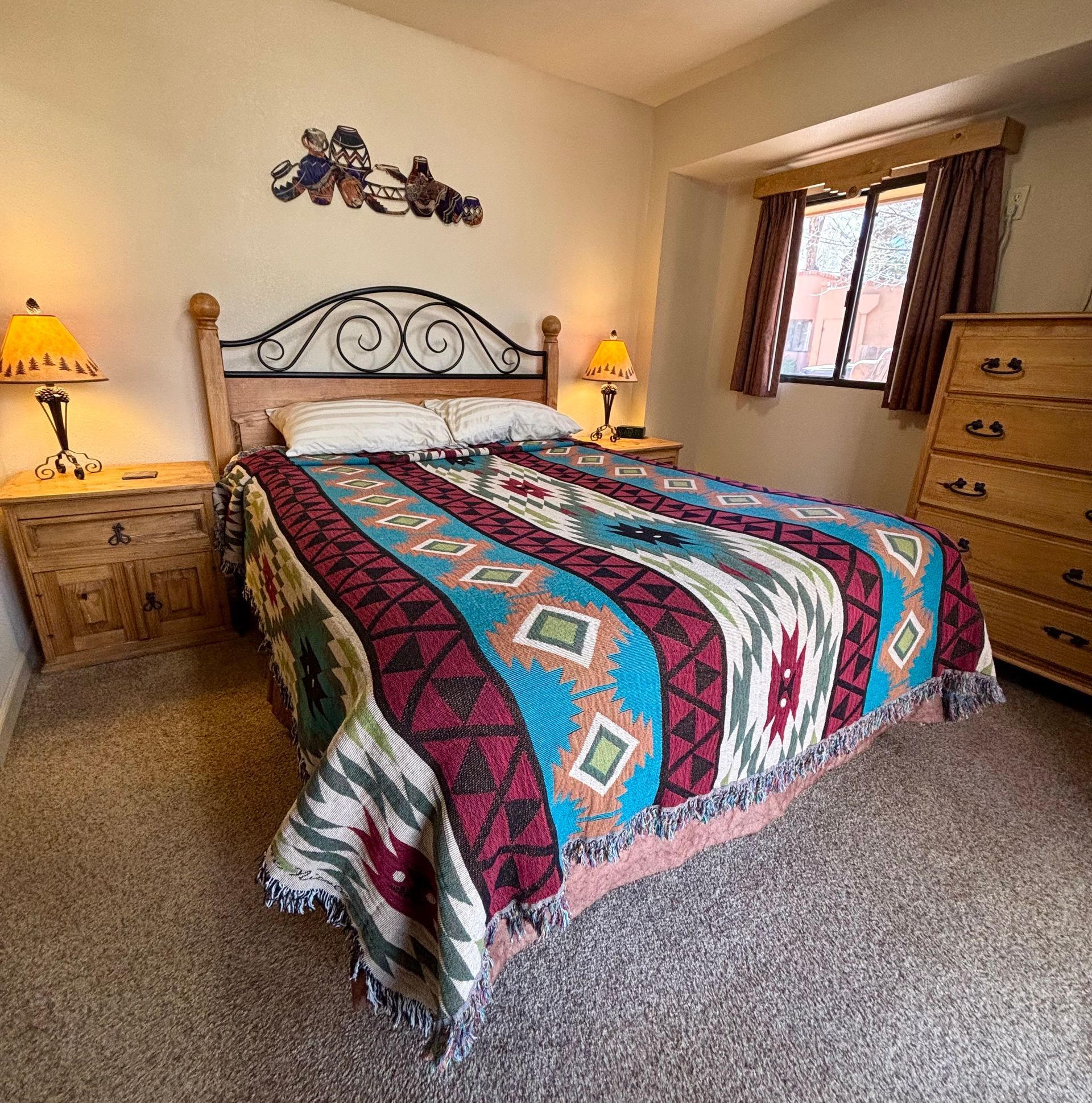 Bedroom with bed, nightstands, dresser, and window. Southwestern style blanket and decor.