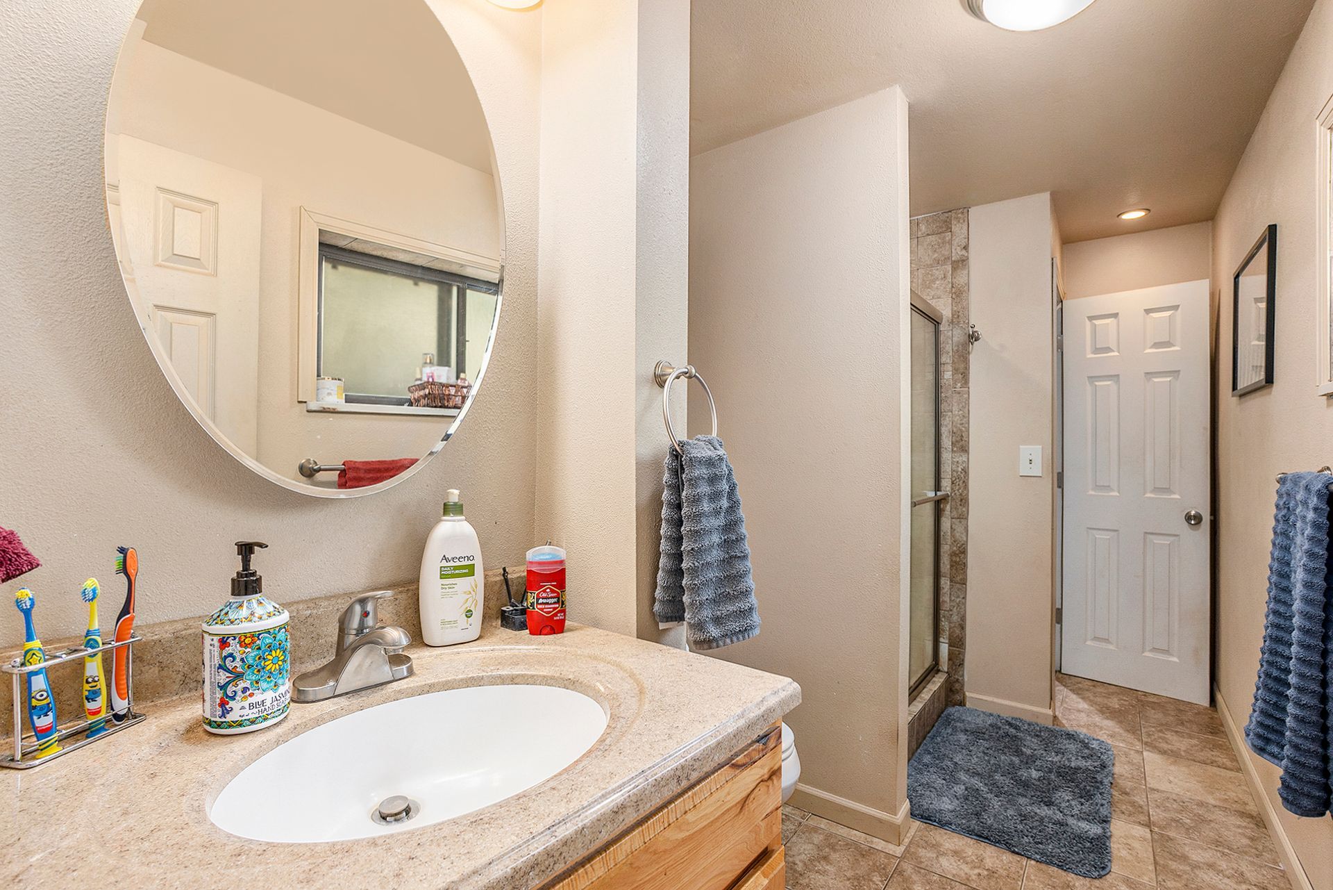 A bathroom with a sink , mirror and shower.