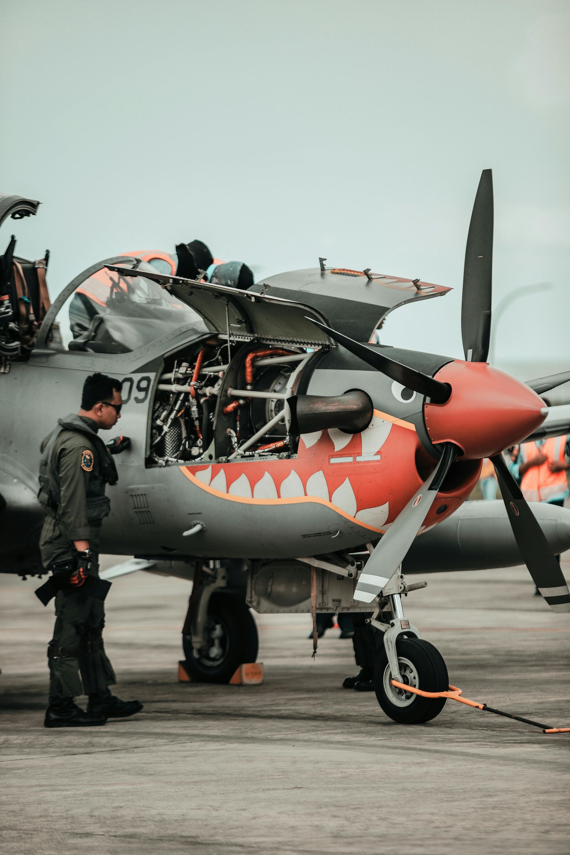A man is standing next to a fighter jet on a runway.