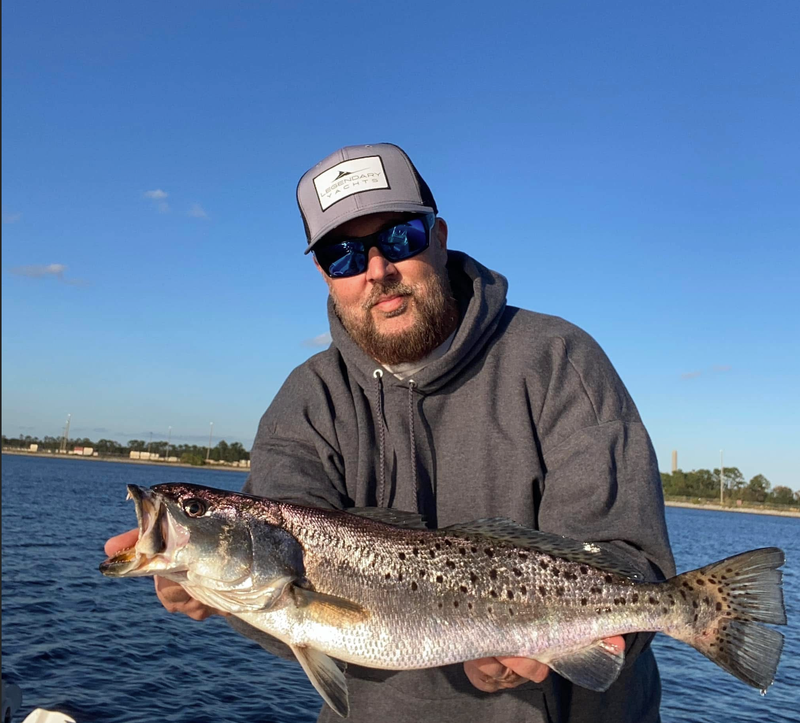 A customer holding a speckled trout on the water