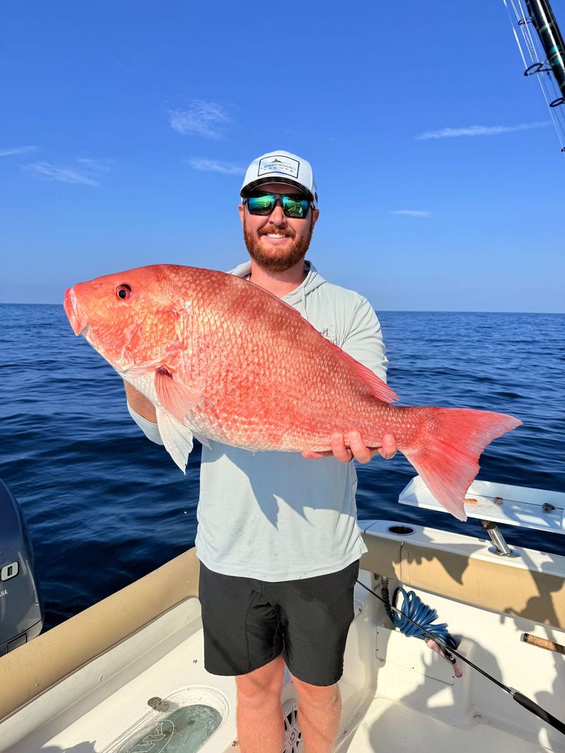 An angler holding a large red snapper offshore