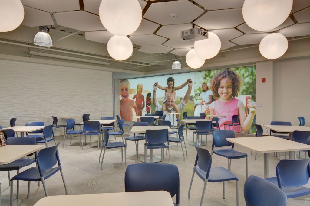 A dining room with tables and chairs and a picture of a family on the wall