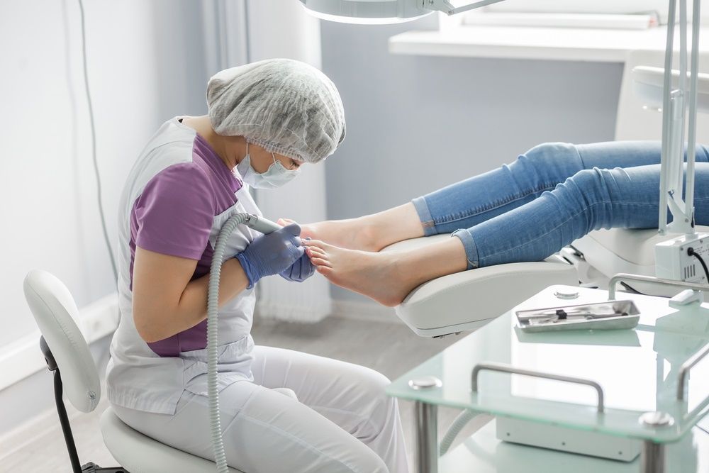 A Woman is Sitting in a Chair Giving a Foot Treatment to a Woman — Maitland Central Podiatry in Maitland NSW