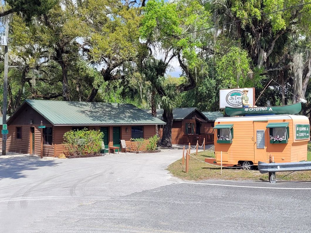 an orange trailer with a canoe on top is parked in front of a cabin