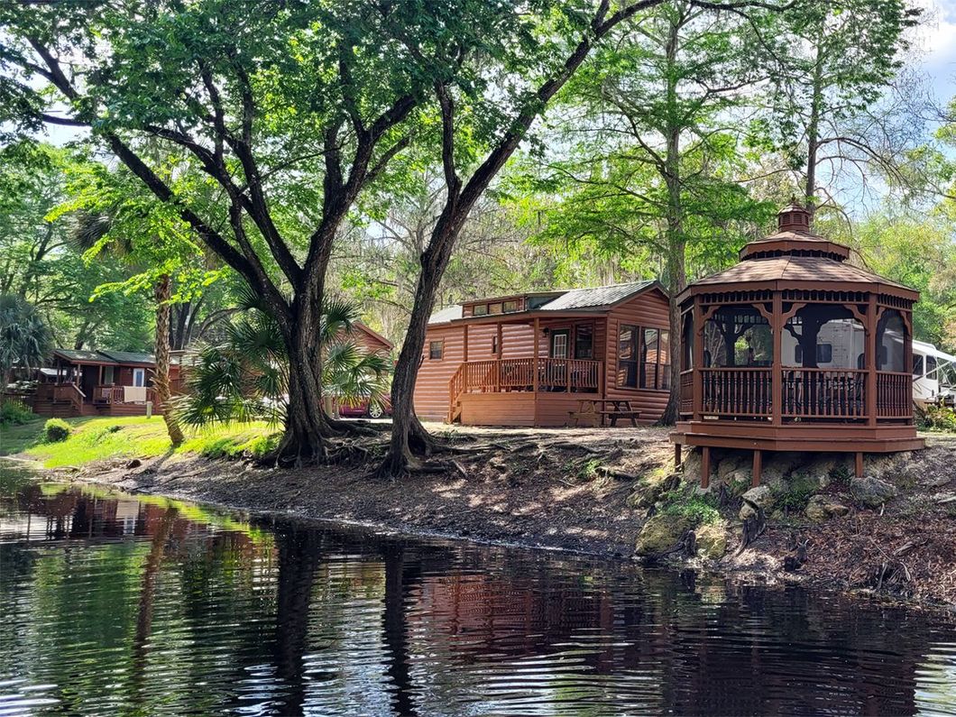 a gazebo sits on the shore of a body of water