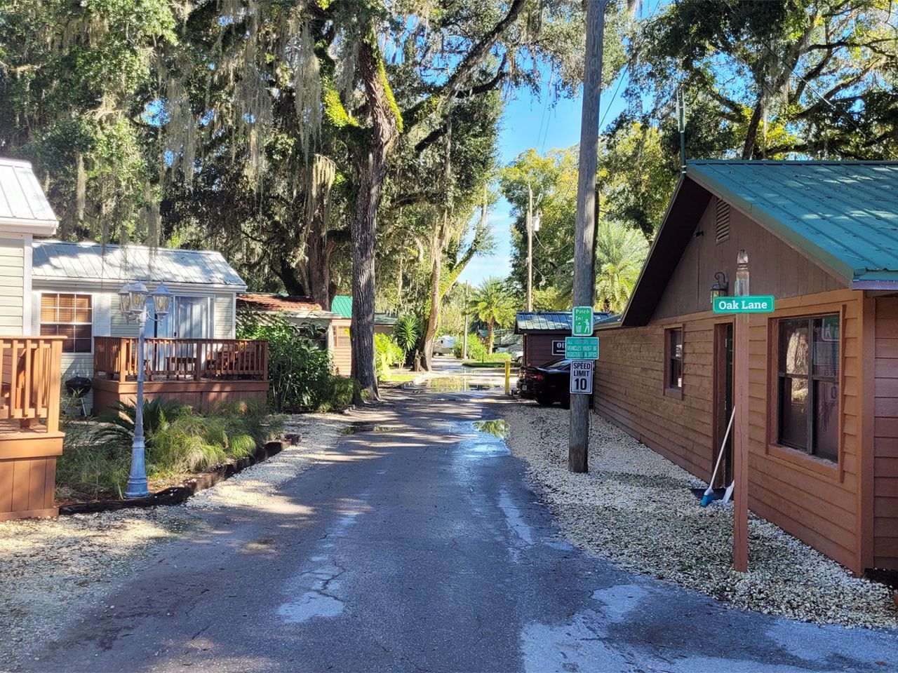 a wooden house with a green roof is sitting on the side of a road .