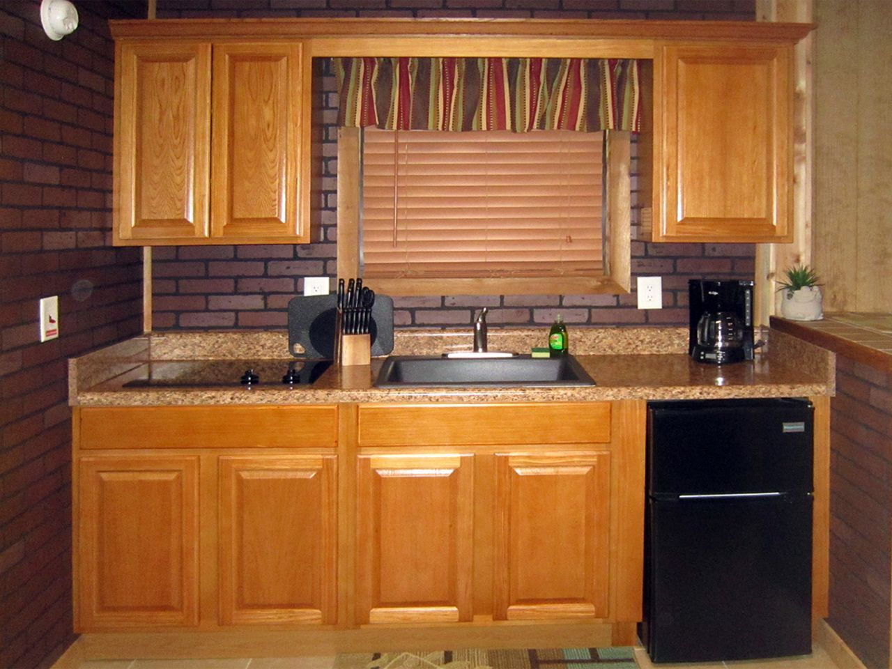 a kitchen with wooden cabinets and a black refrigerator