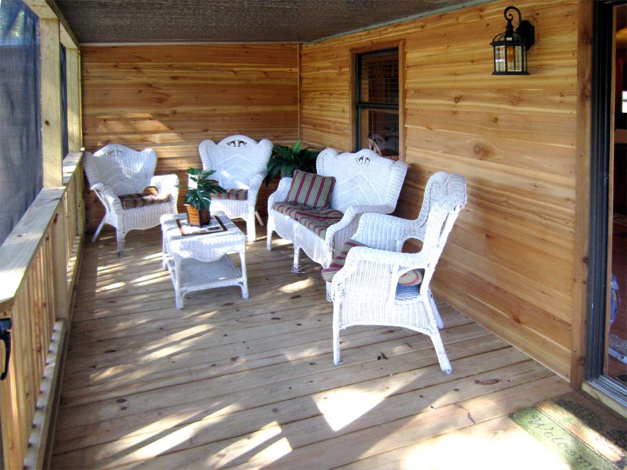 a screened in porch with white wicker furniture