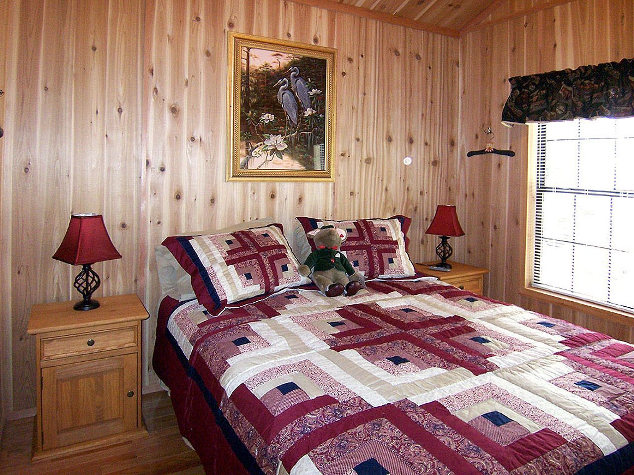 a bedroom with a bed , two lamps and a teddy bear