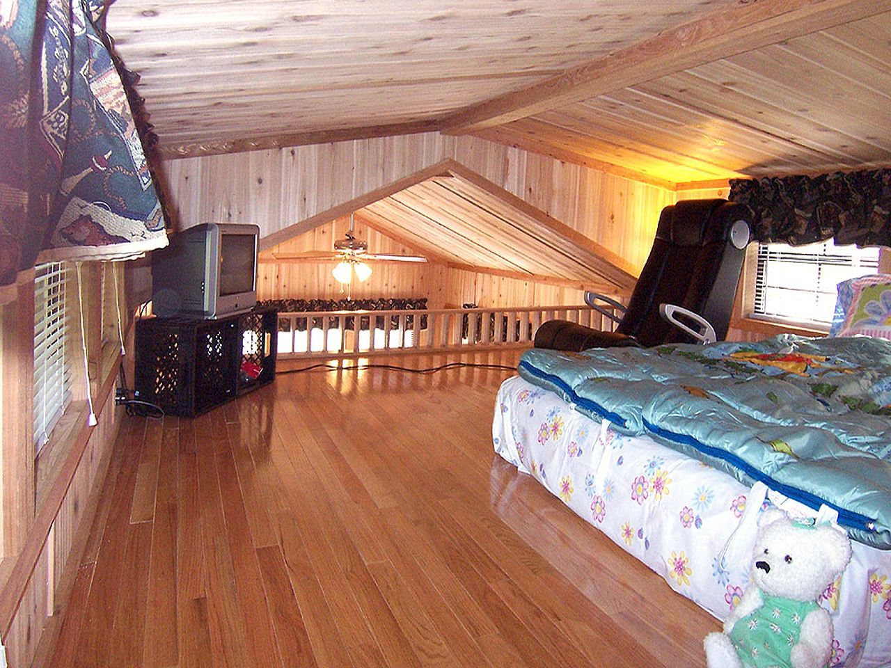 a bedroom with a bed a television and a teddy bear