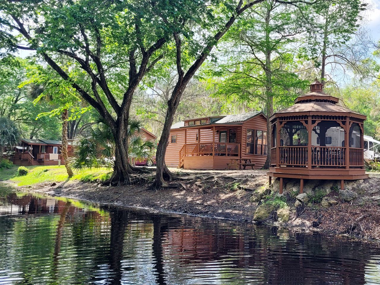 a gazebo is sitting on the shore of a lake next to a cabin .