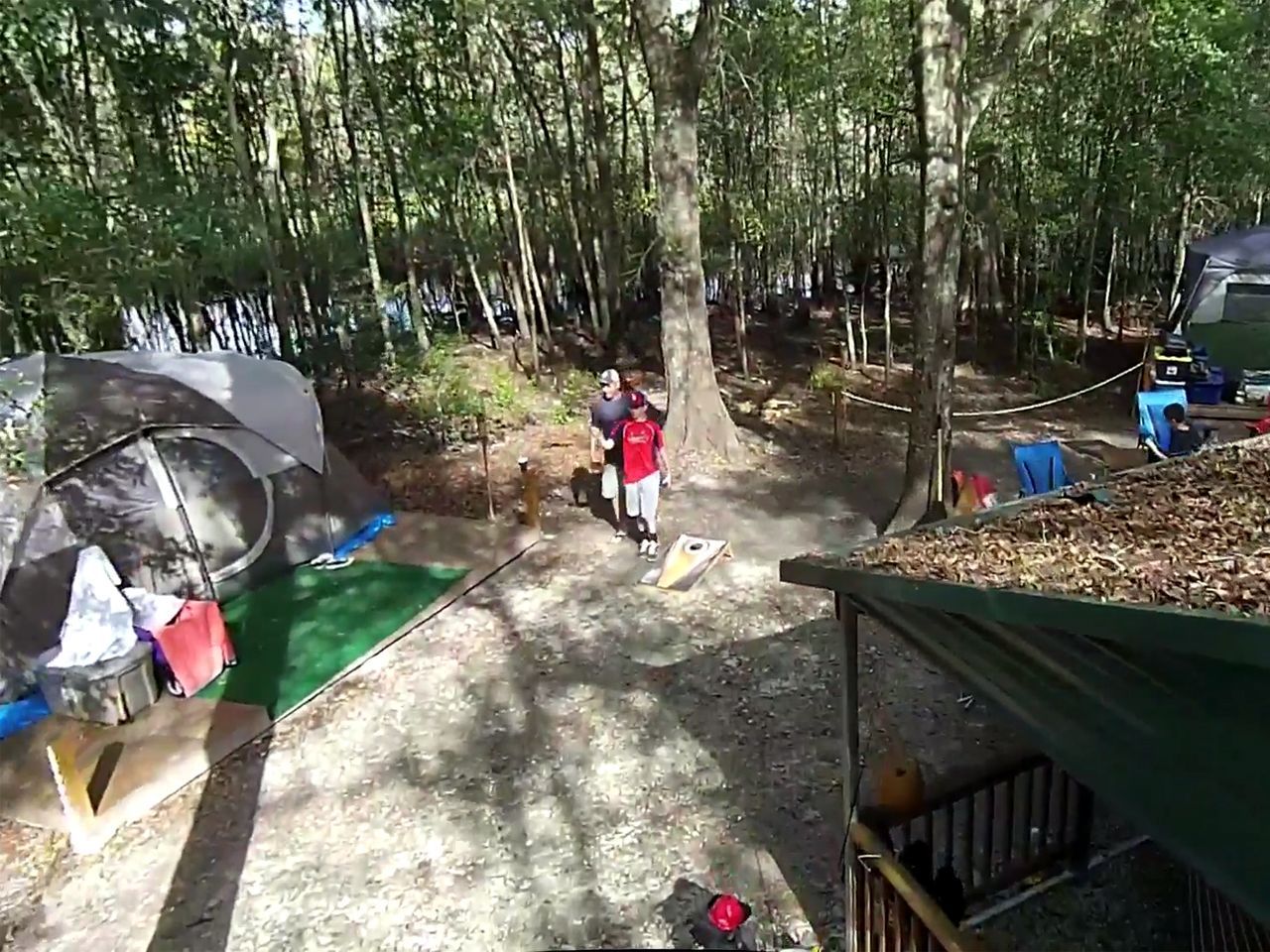 a group of people are standing in a campground in the woods .