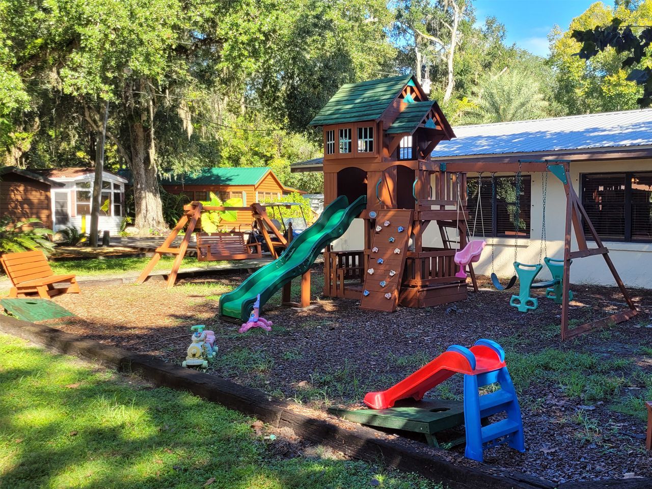a playground with a slide and swings in front of a house .