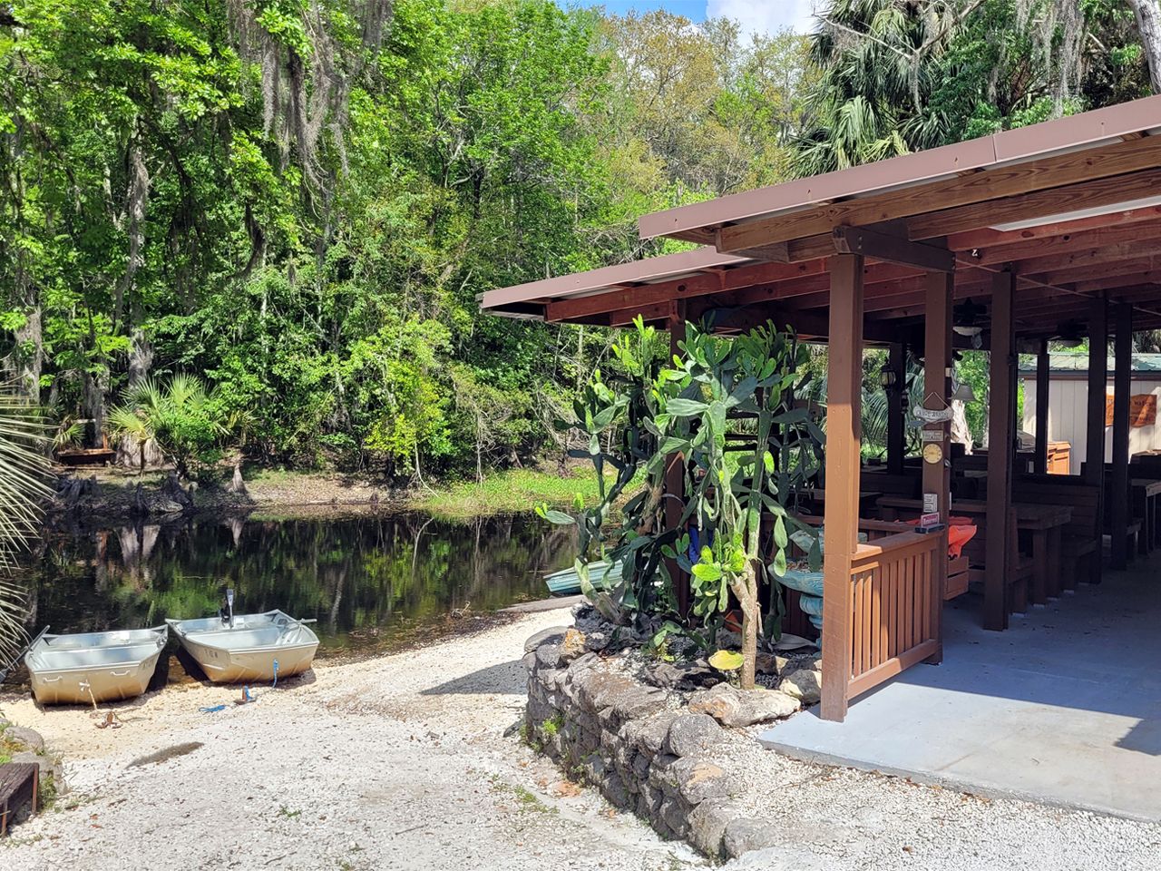 a wooden building with a covered area and a pond in the background .