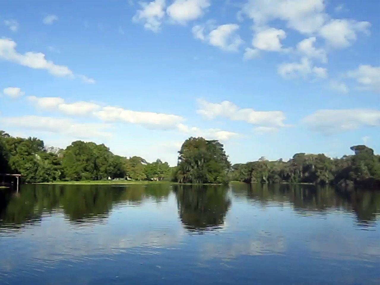 a lake surrounded by trees on a sunny day