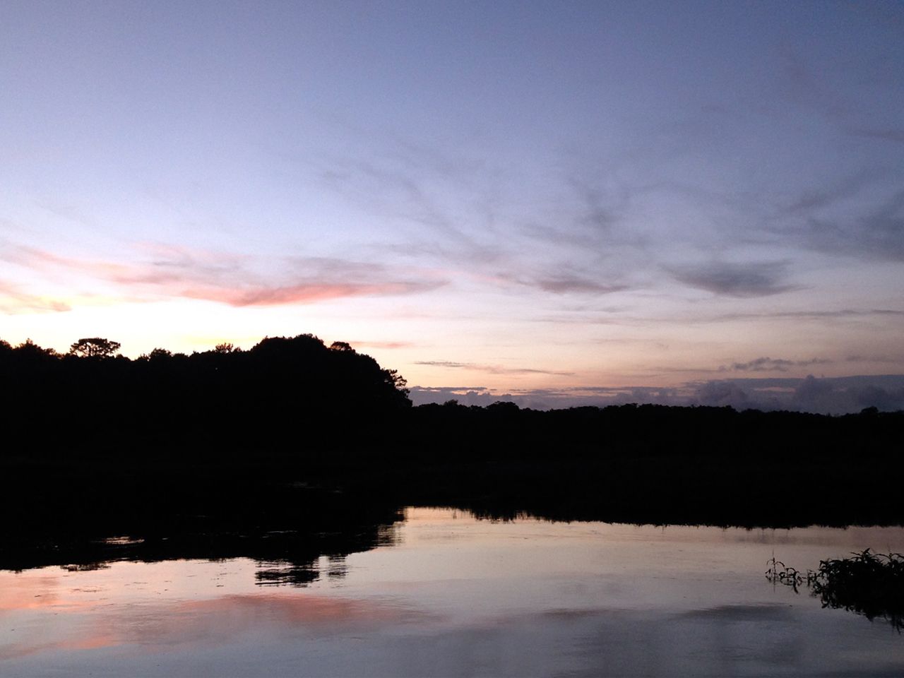 a sunset over a lake with trees in the background