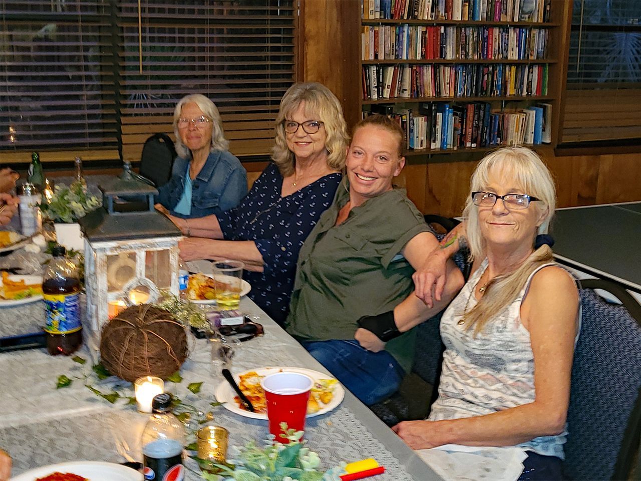 a group of women are sitting at a table with plates of food .
