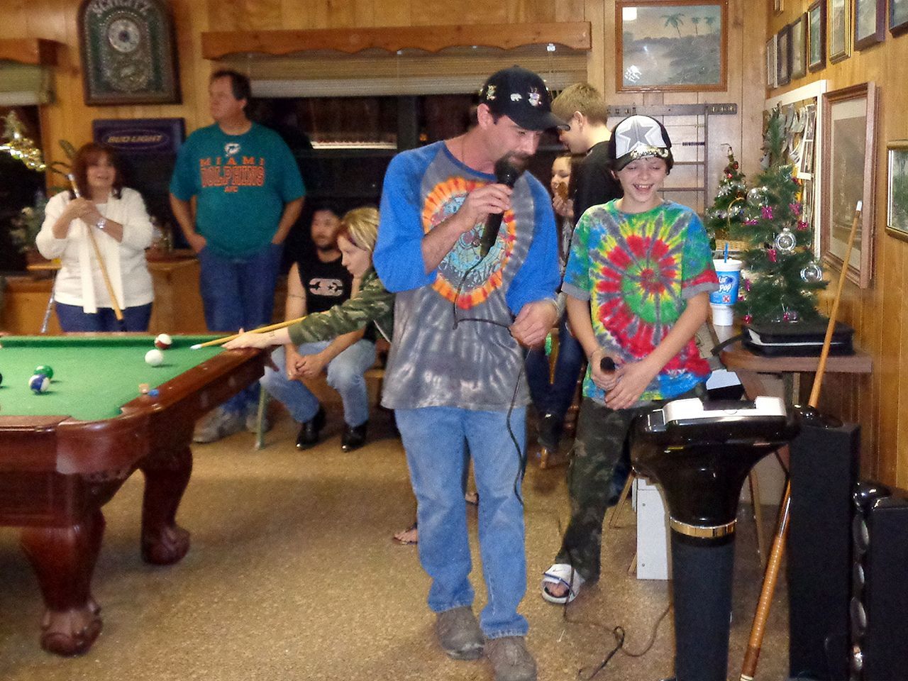 a man singing into a microphone in front of a pool table