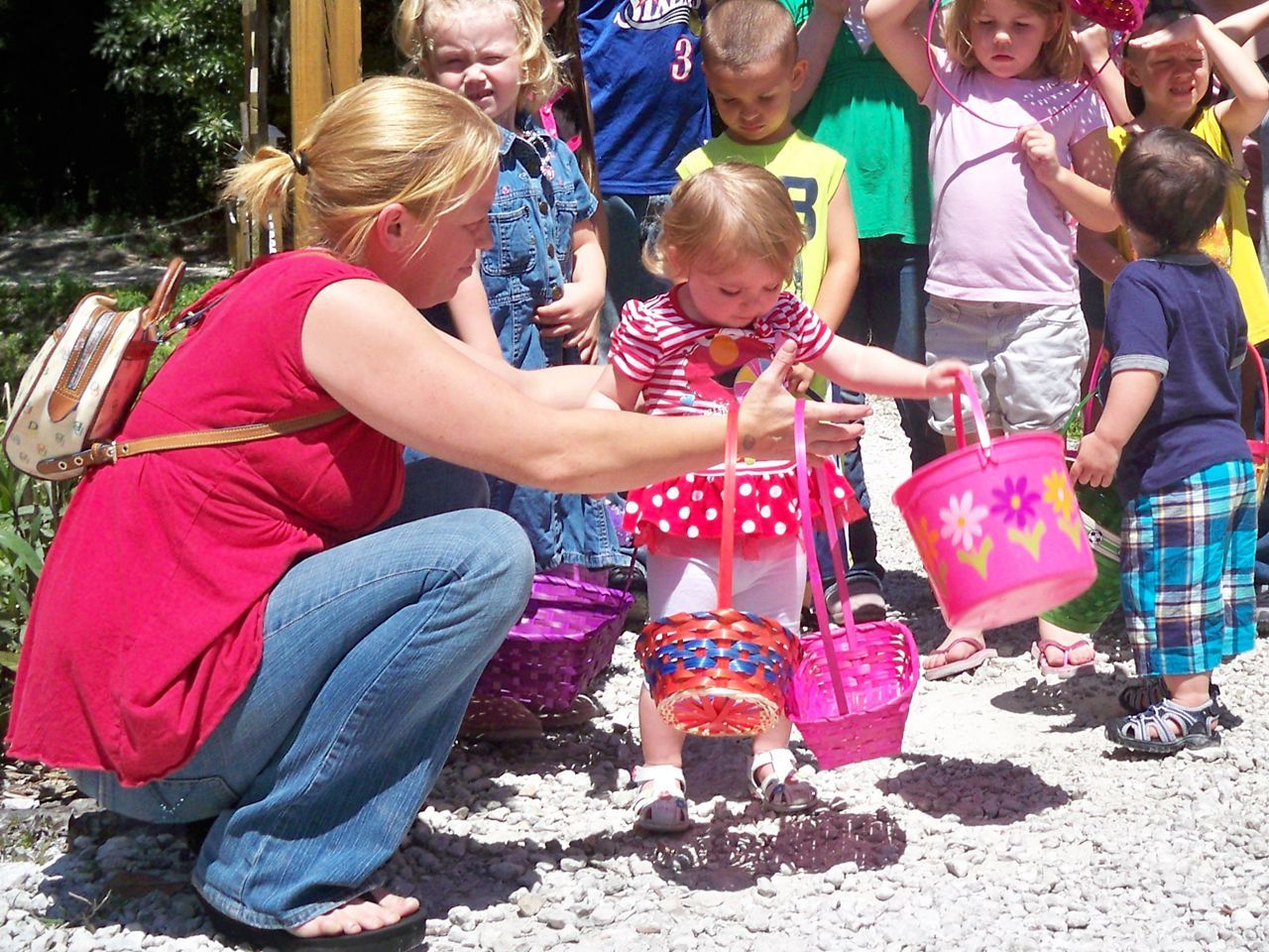 a group of children are gathered around a woman kneeling down
