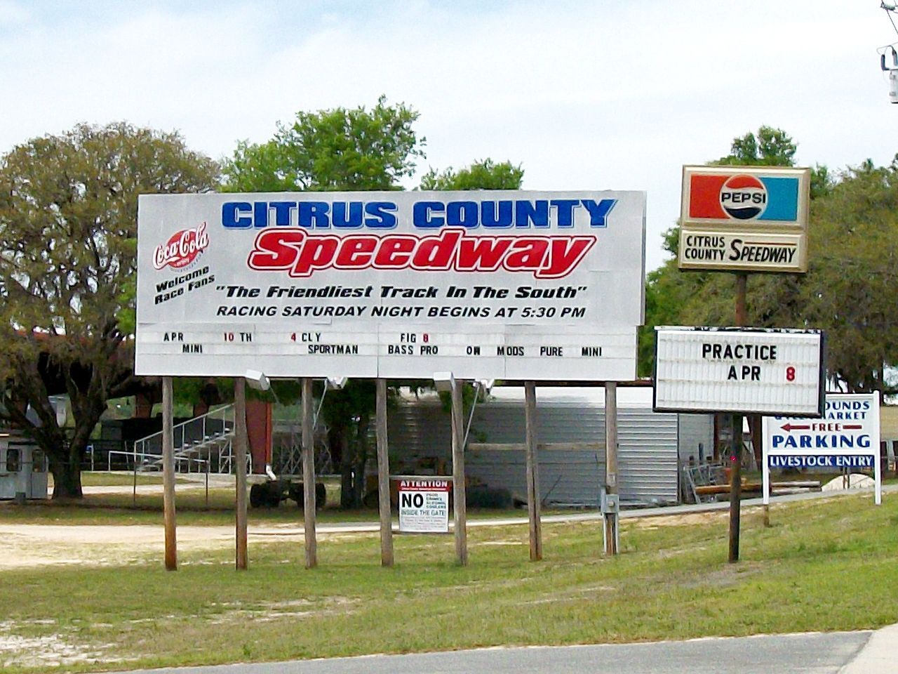 a billboard for citrus county speedway is in a grassy area