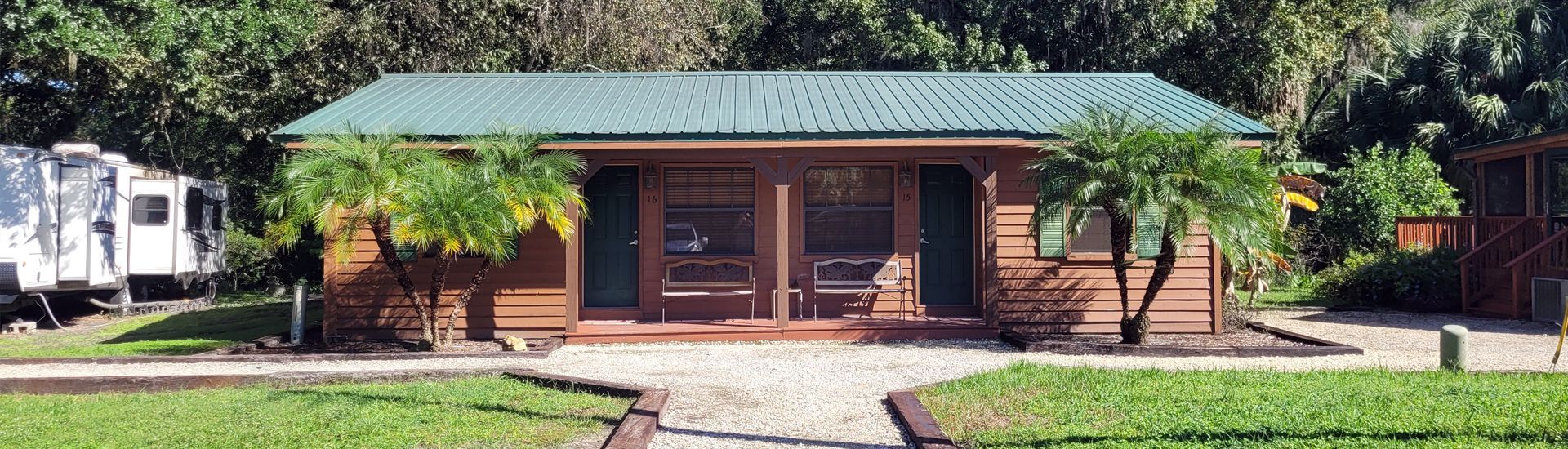a small log cabin with a green roof is sitting in the middle of a lush green field .