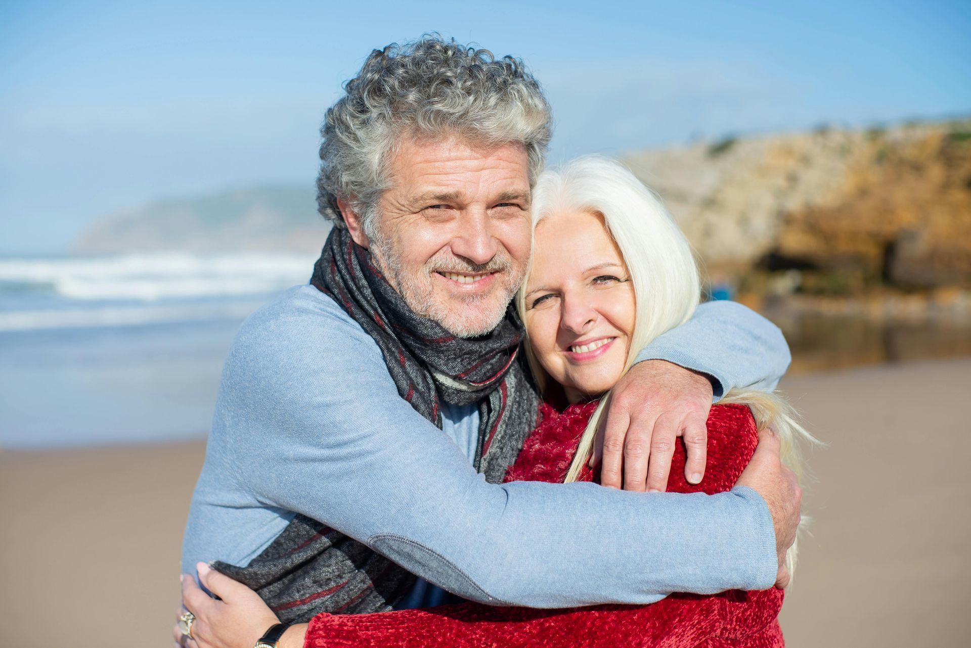 An older couple is dancing on the beach.
