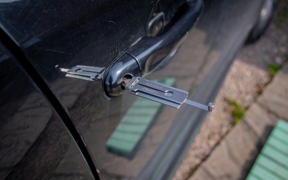 A lock picking tool in the lock of a car door.