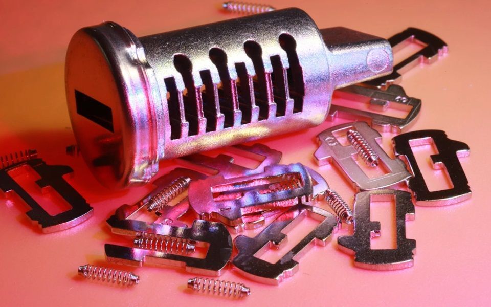 Lock tumbler with pins and springs scattered next to it.