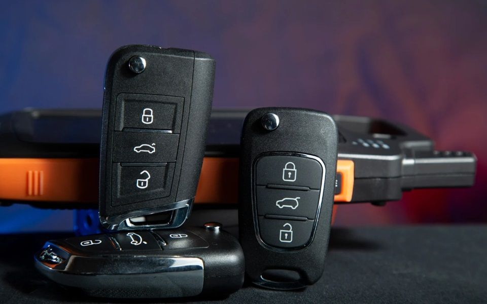 Three transponder keys leaning against a reprogramming device.