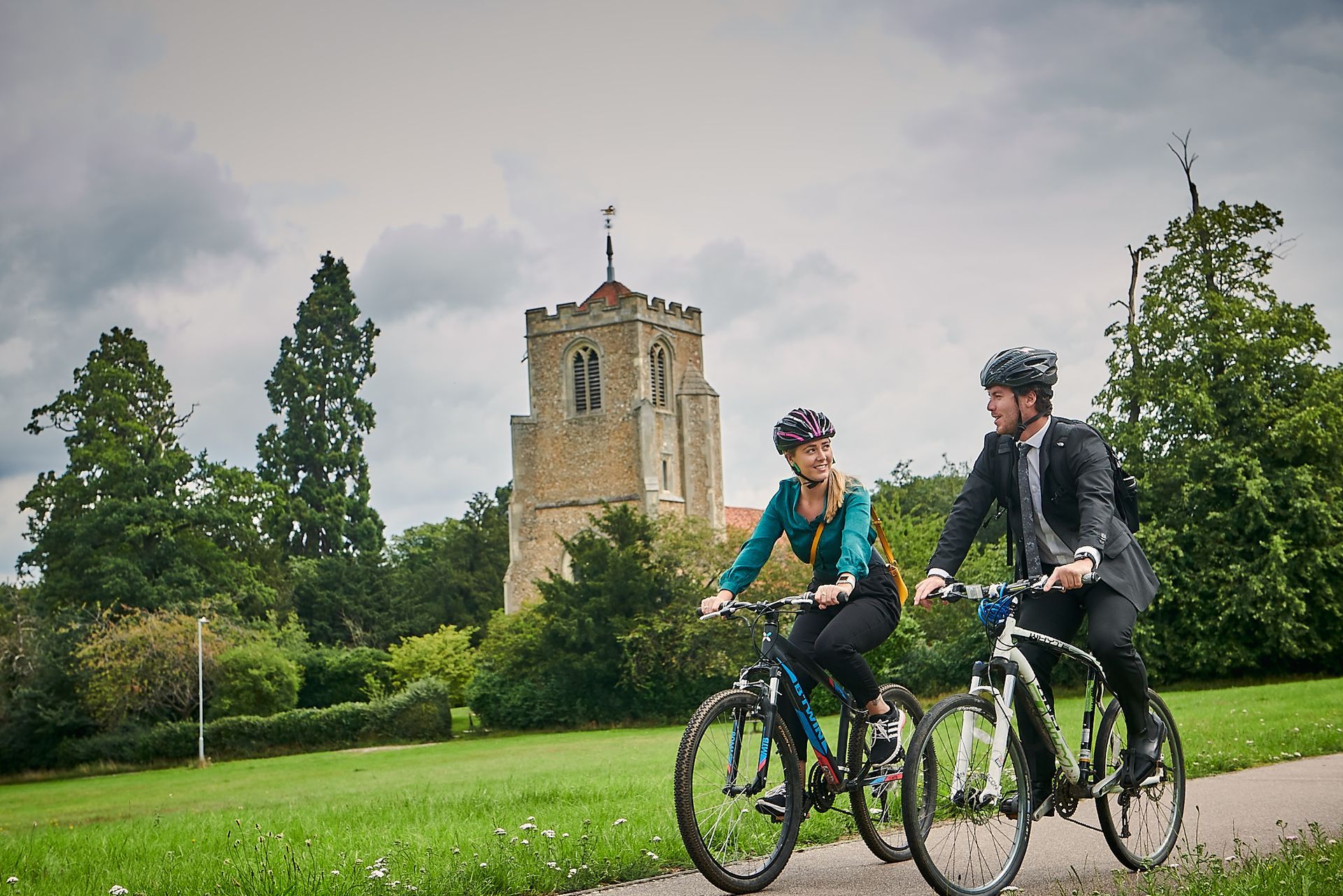 A man and a woman are riding bicycles in a park.