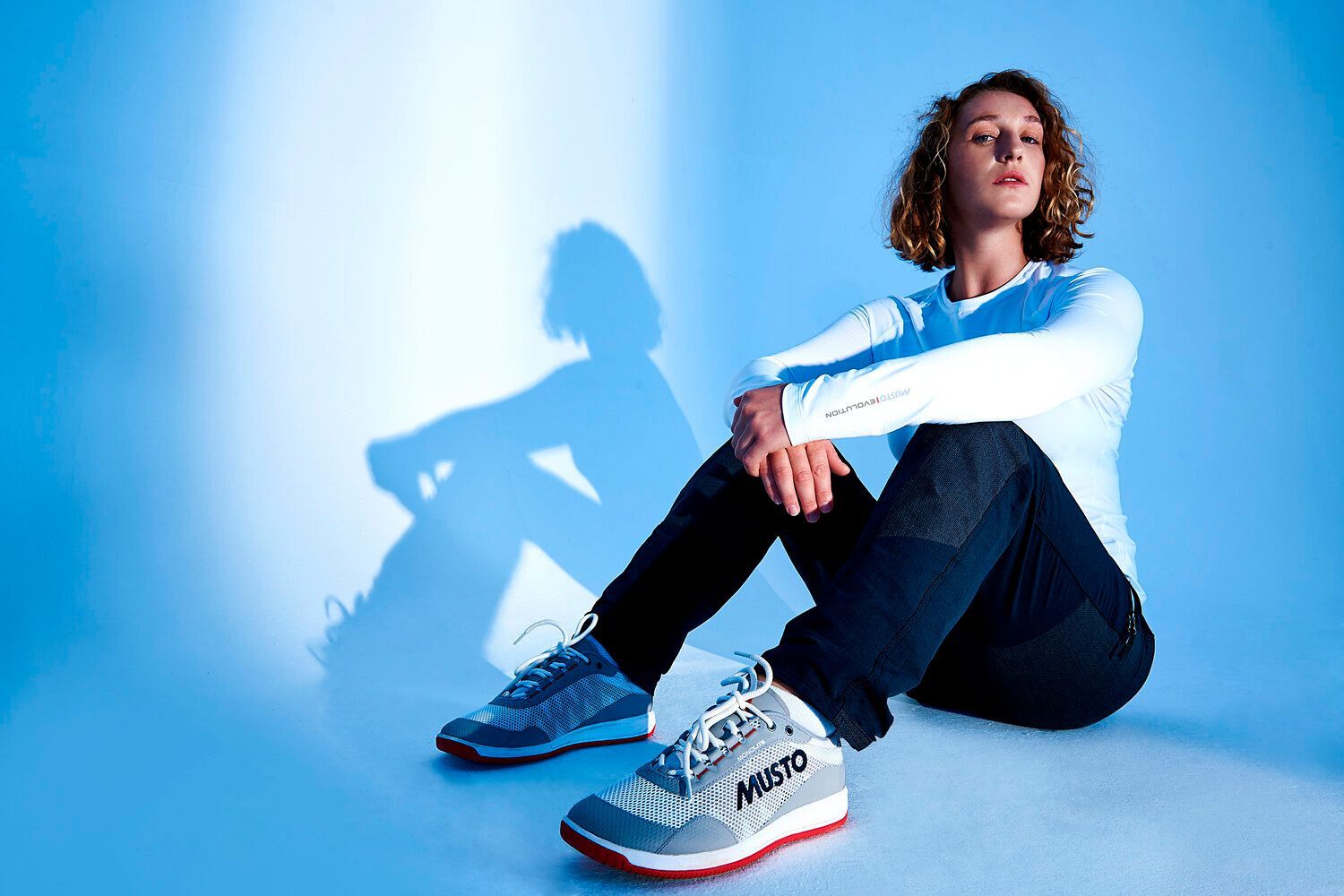 A woman is sitting on the floor with her legs crossed.