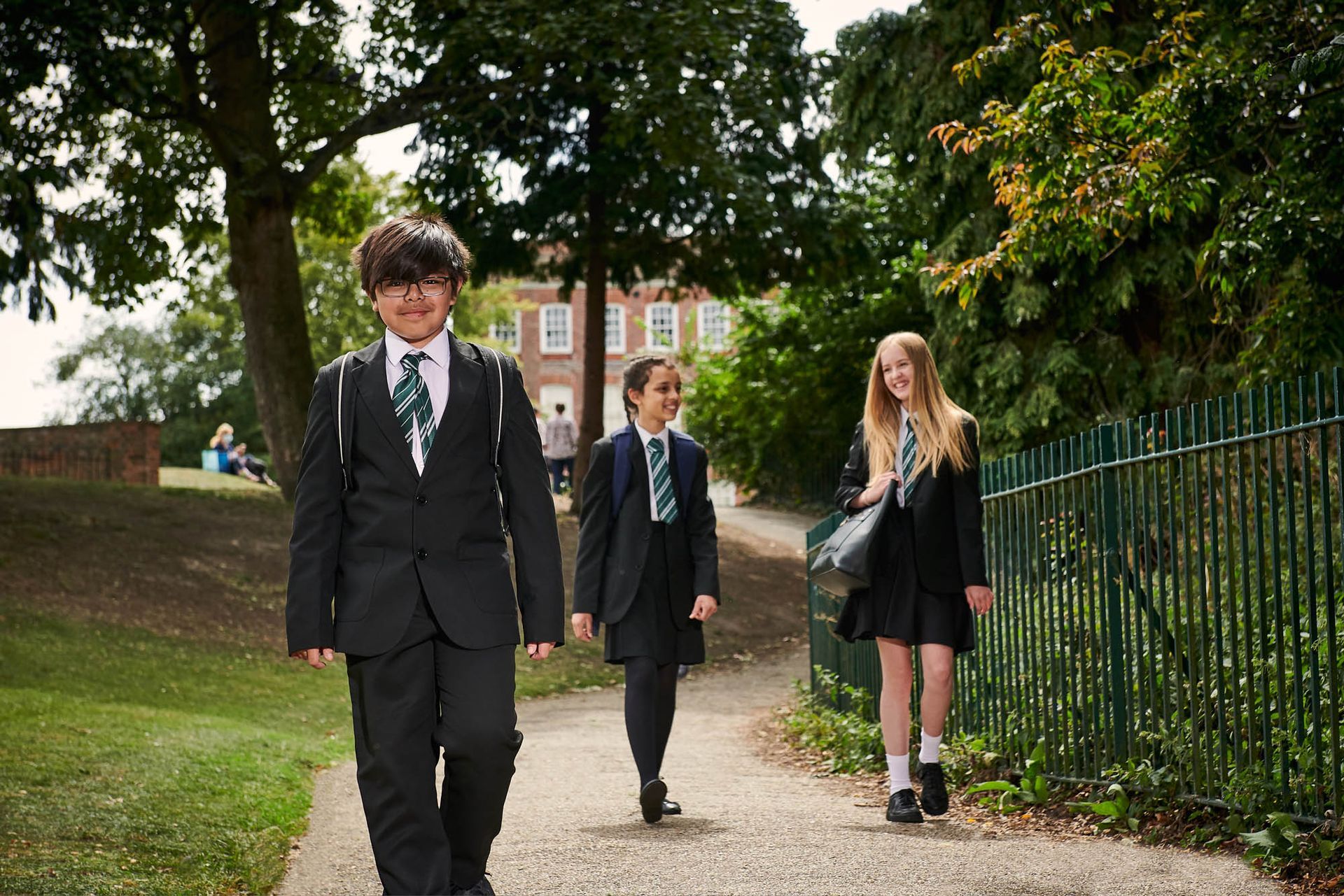 A group of children in school uniforms are walking down a path.