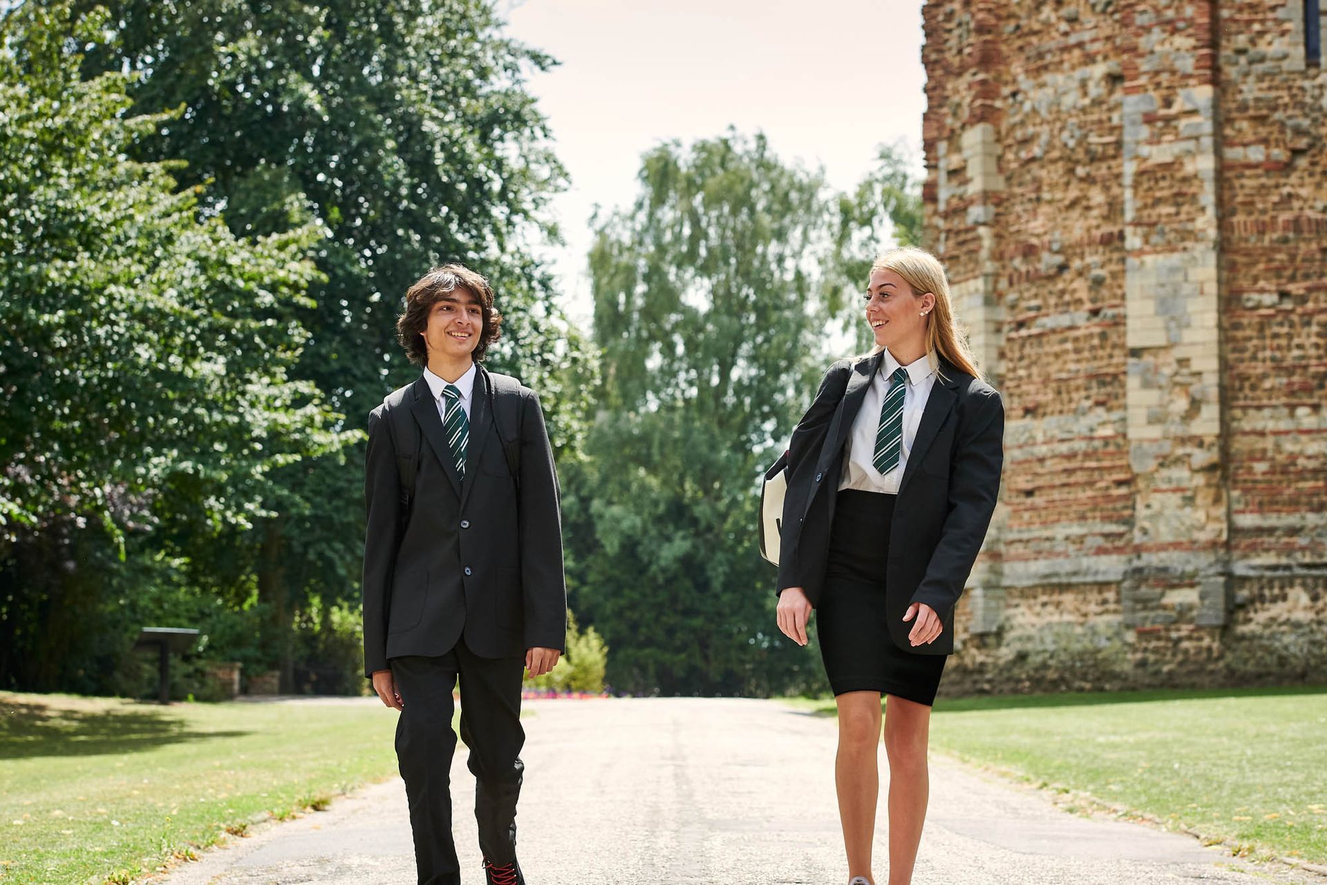 A boy and a girl in school uniforms are walking down a path.