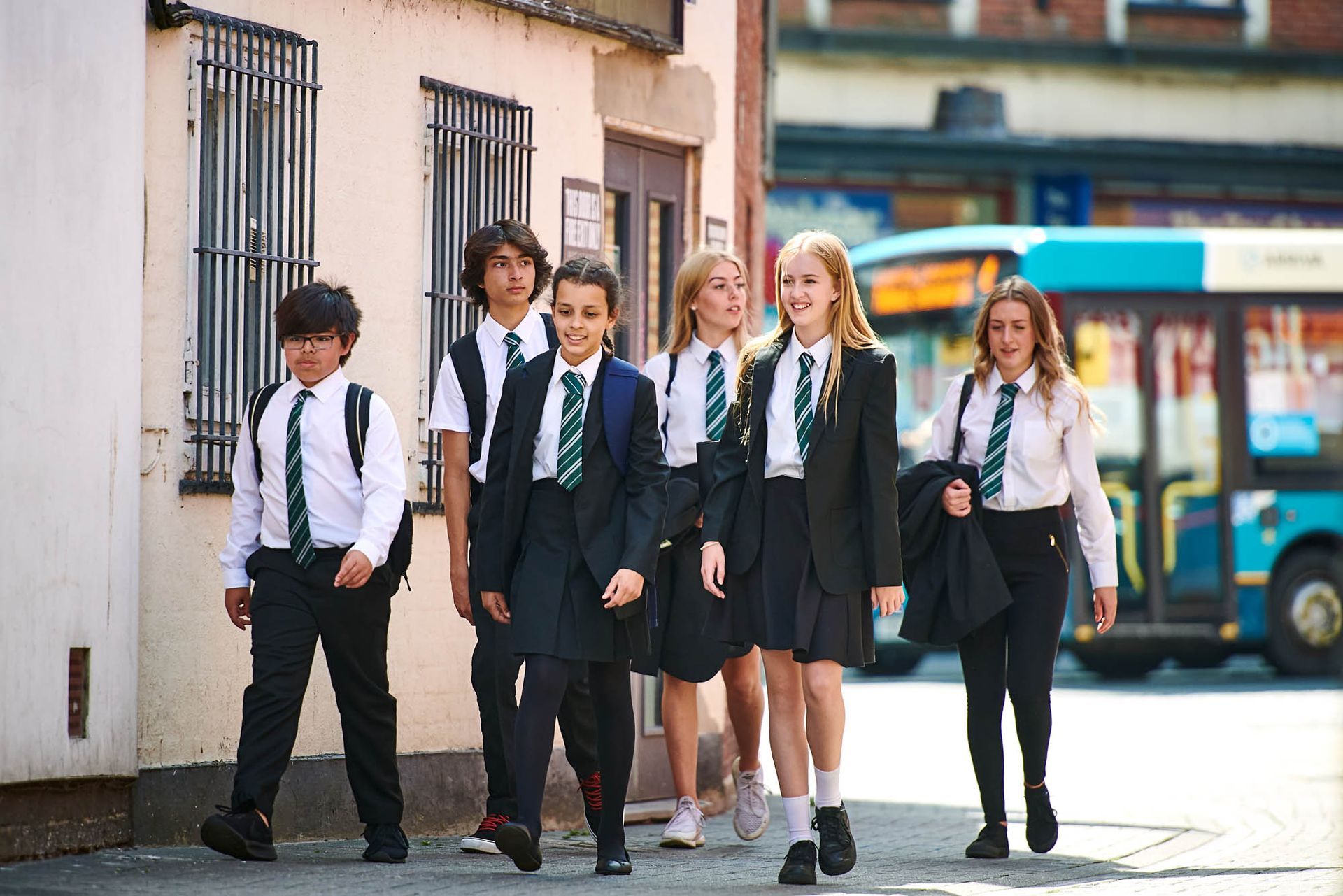 A group of children in school uniforms are walking down the street.