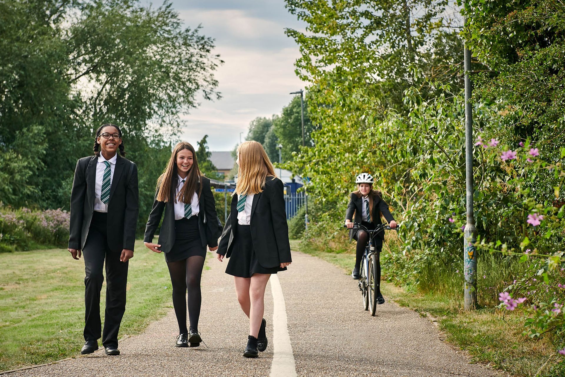 A group of children in school uniforms are walking down a path.