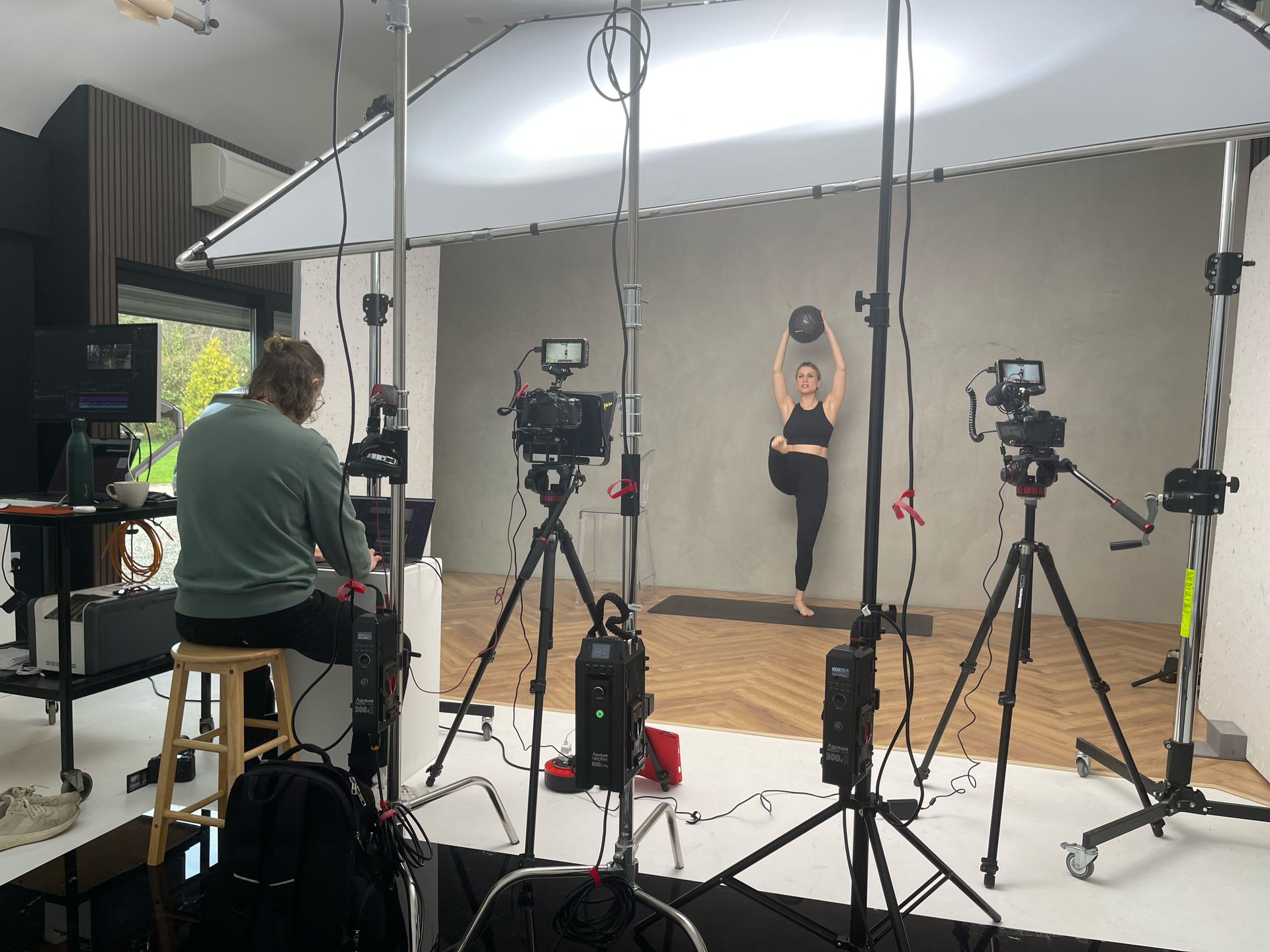A woman is doing yoga in front of a camera in a studio.