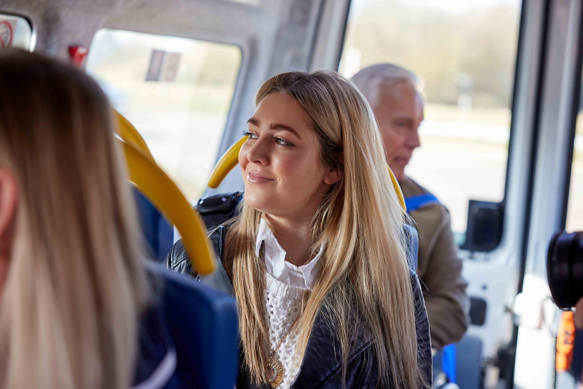 A woman is sitting on a bus with other people.