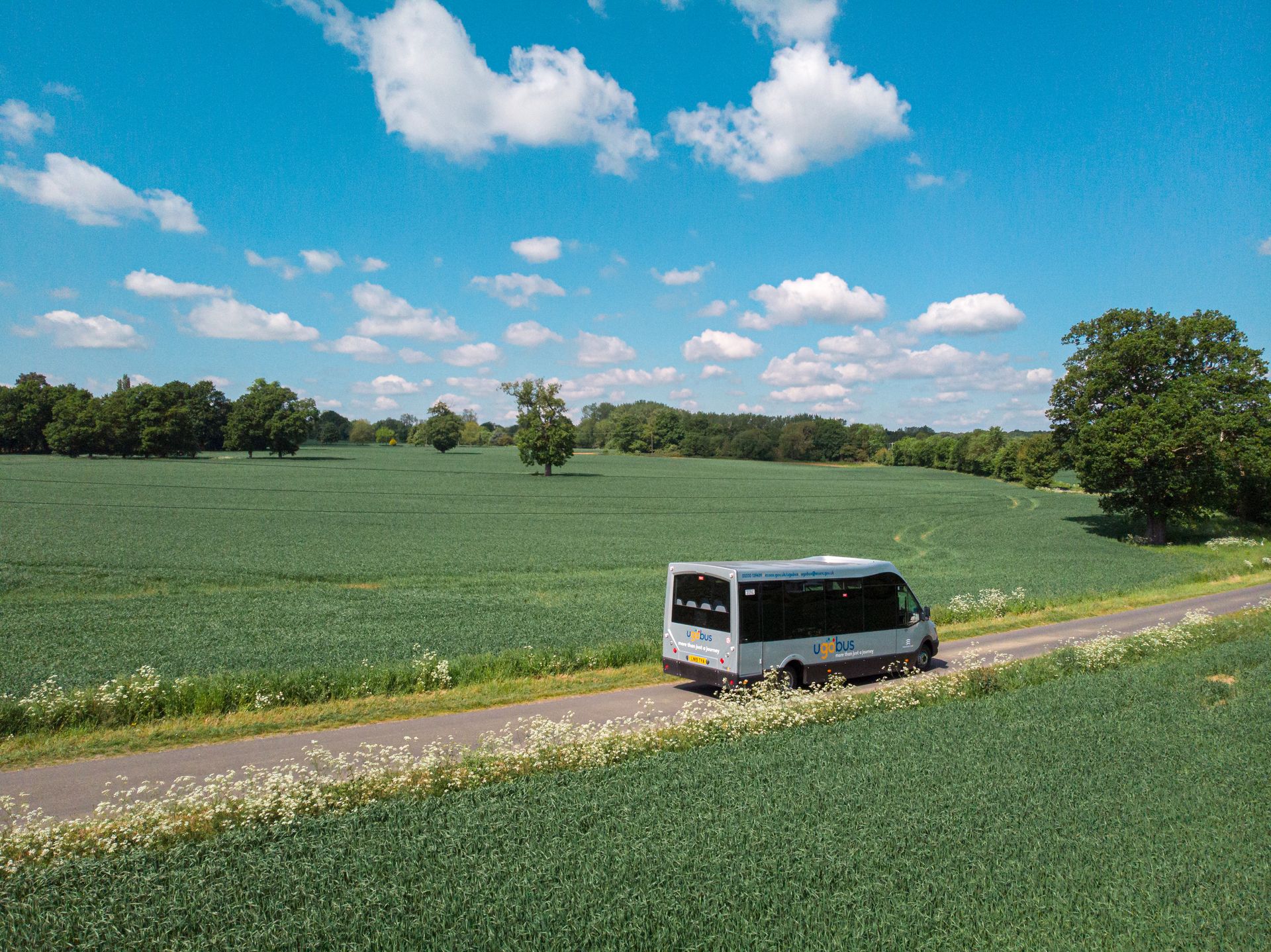 An aerial view of a bus driving down a country road.