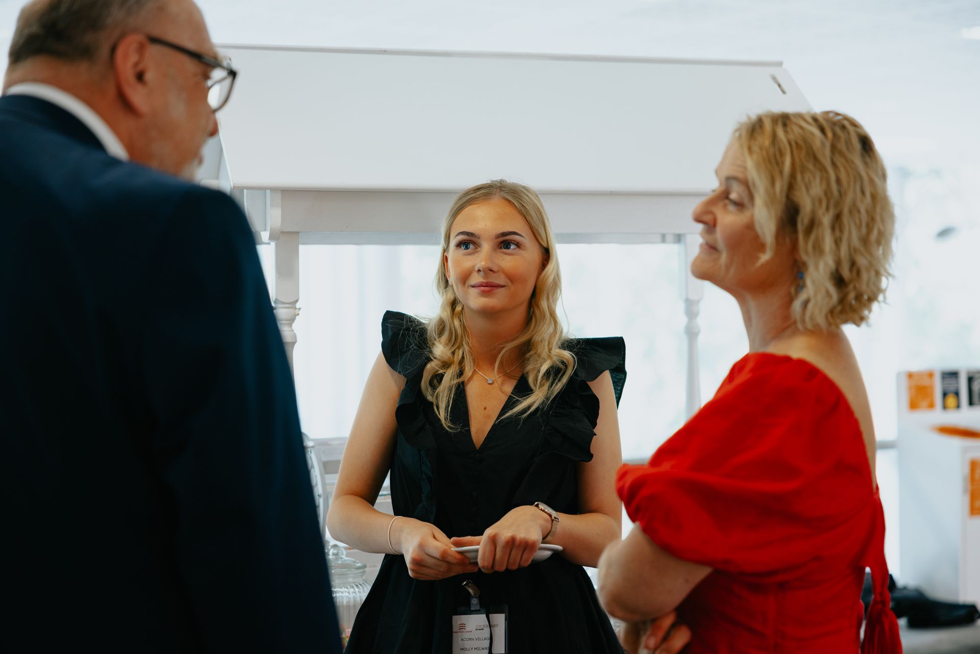 Three women are standing next to each other talking to a man in a suit.