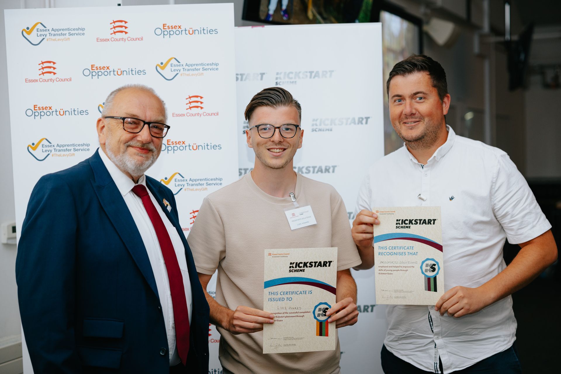 Three men are standing next to each other holding certificates.