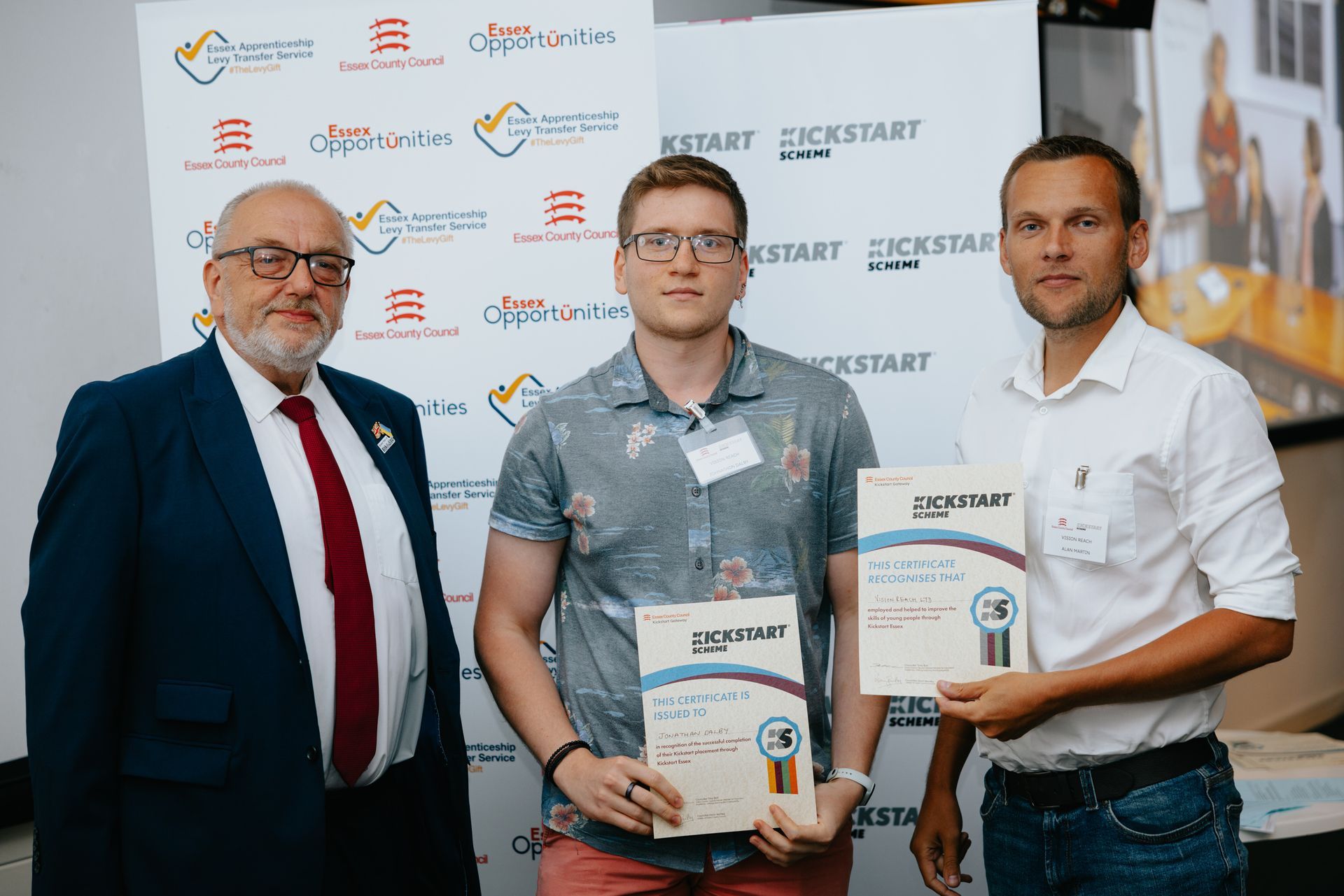 Three men are standing next to each other holding certificates.