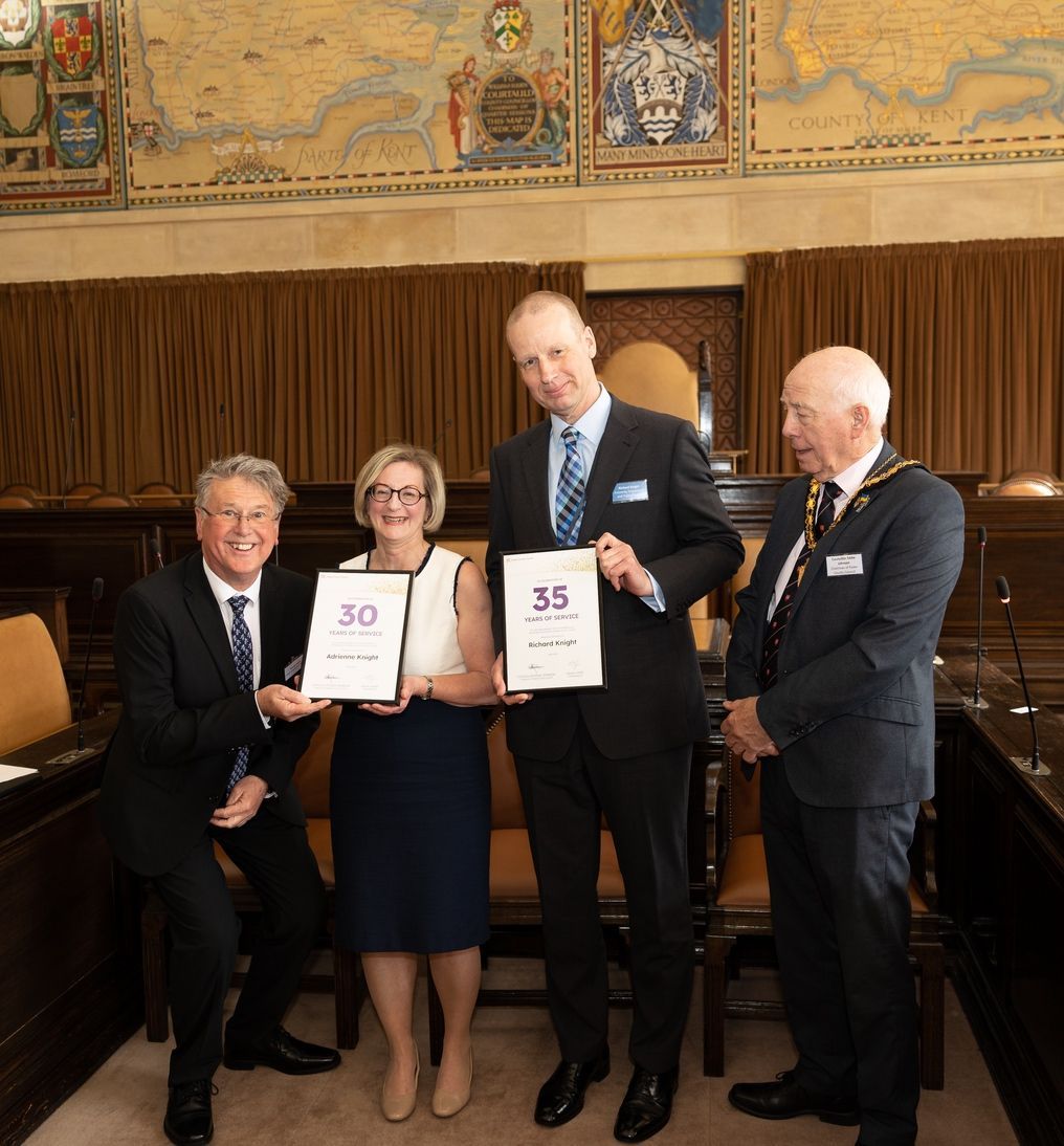 A group of men and women are standing in a room holding certificates.