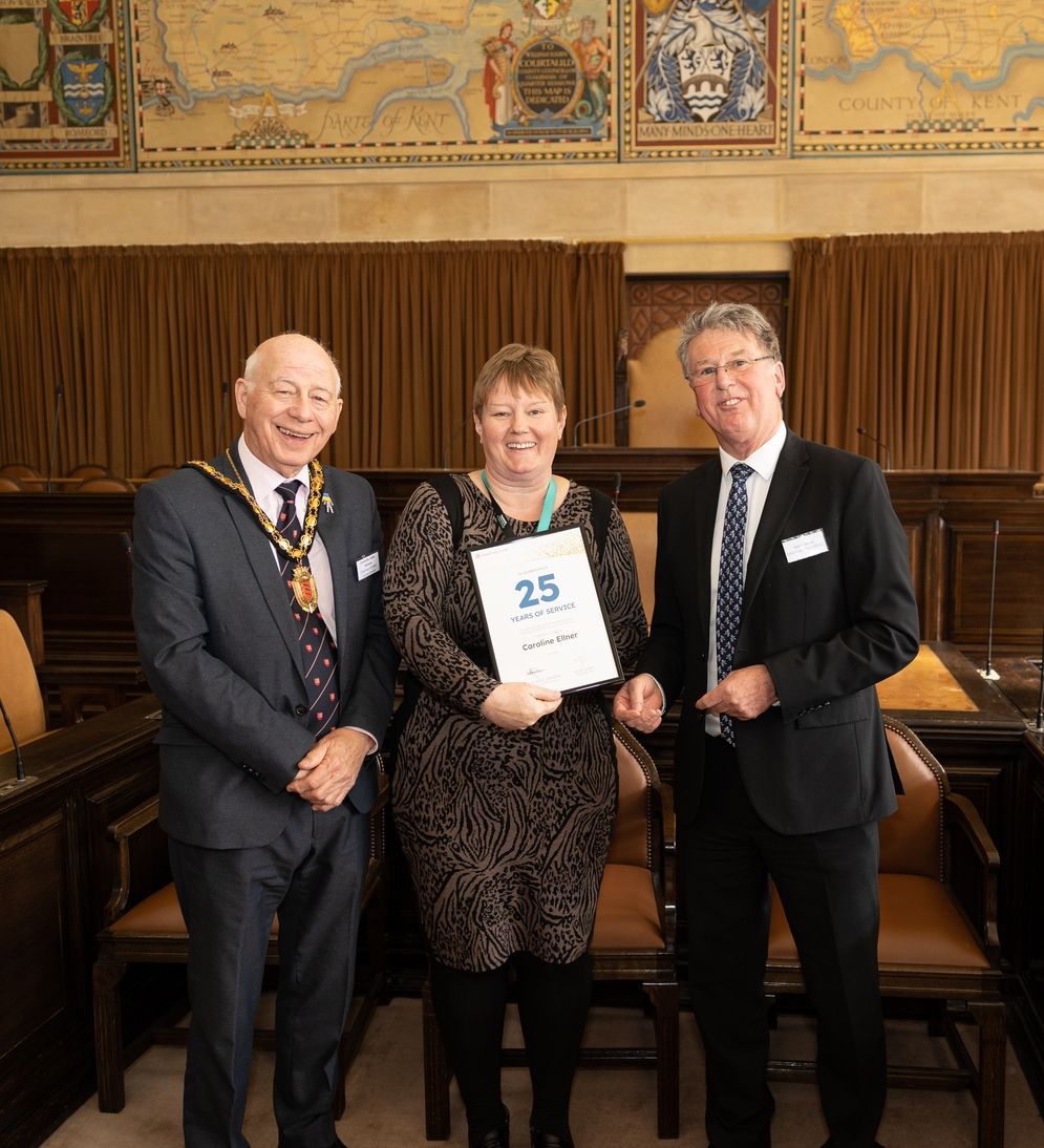 Three men and a woman are posing for a picture in a room.
