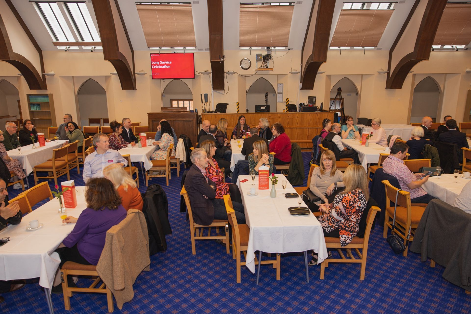 A group of people are sitting at tables in a large room.