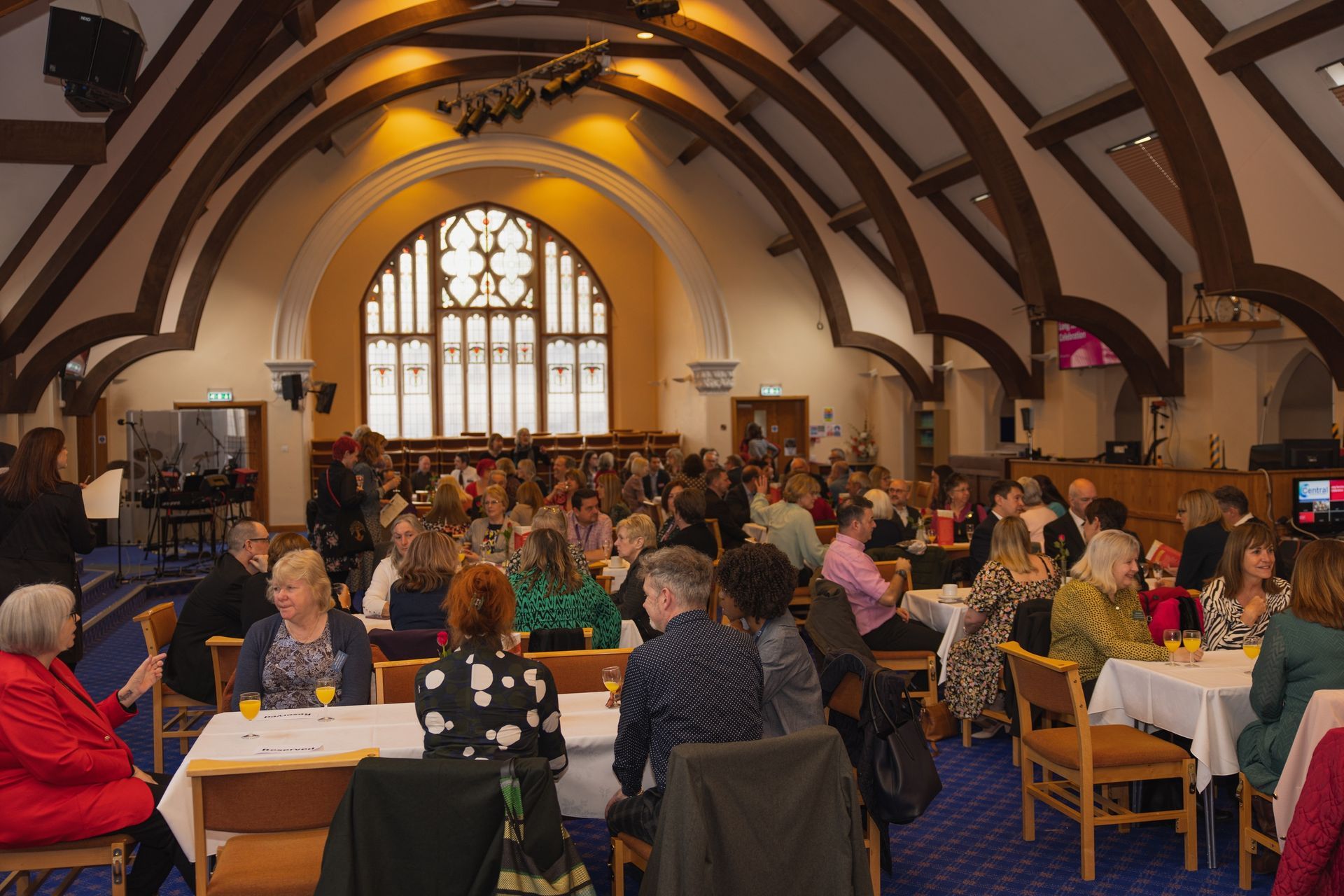 A large group of people are sitting at tables in a large room.