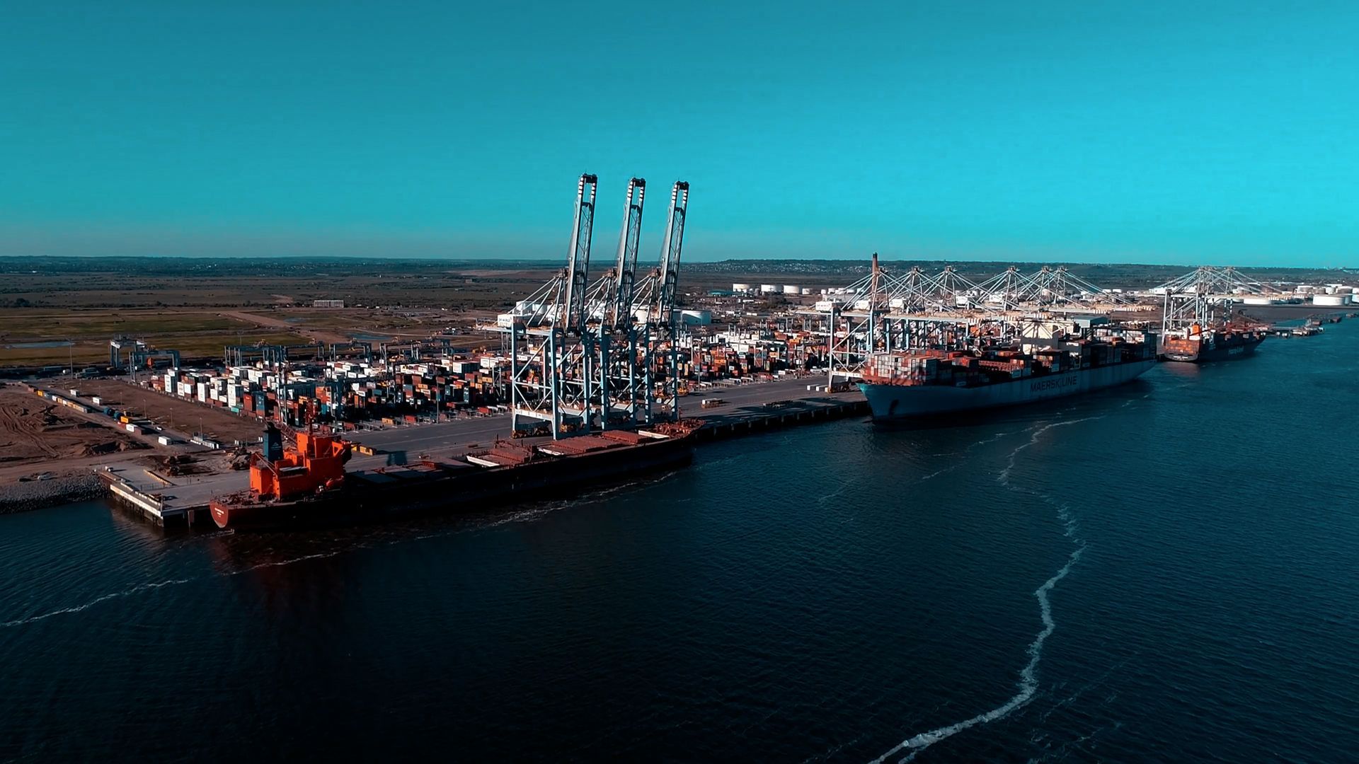 An aerial view of a large container ship docked in a harbor.